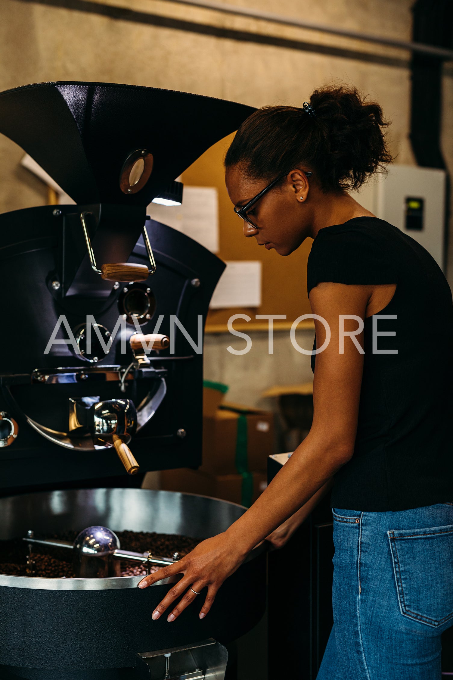 Female business owner standing at modern coffee bean roasting machine	