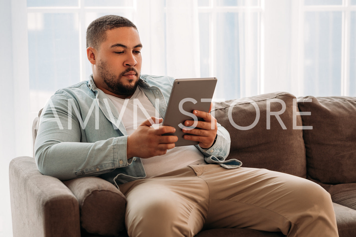 Young man using digital tablet surfing the internet on the couch