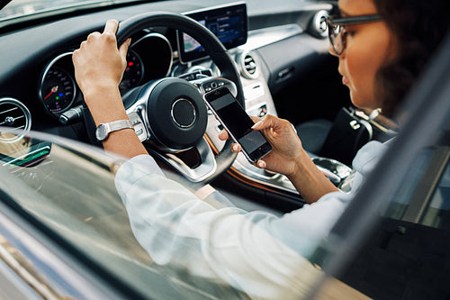 Unrecognizable woman using smartphone while sitting in car.