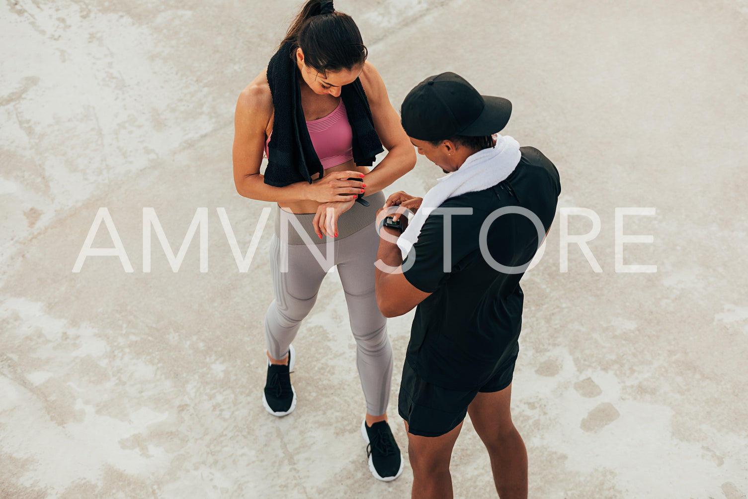 Shot from above on two athletes checking their smartwatch after training. Fitness couple adjusting fitness trackers.