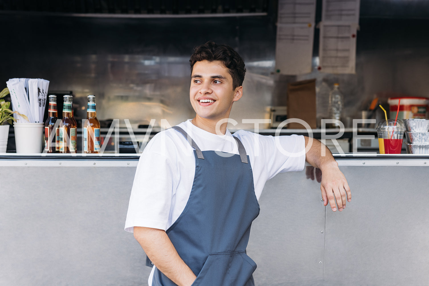 Portrait of a young waiter standing at a food truck and looking away