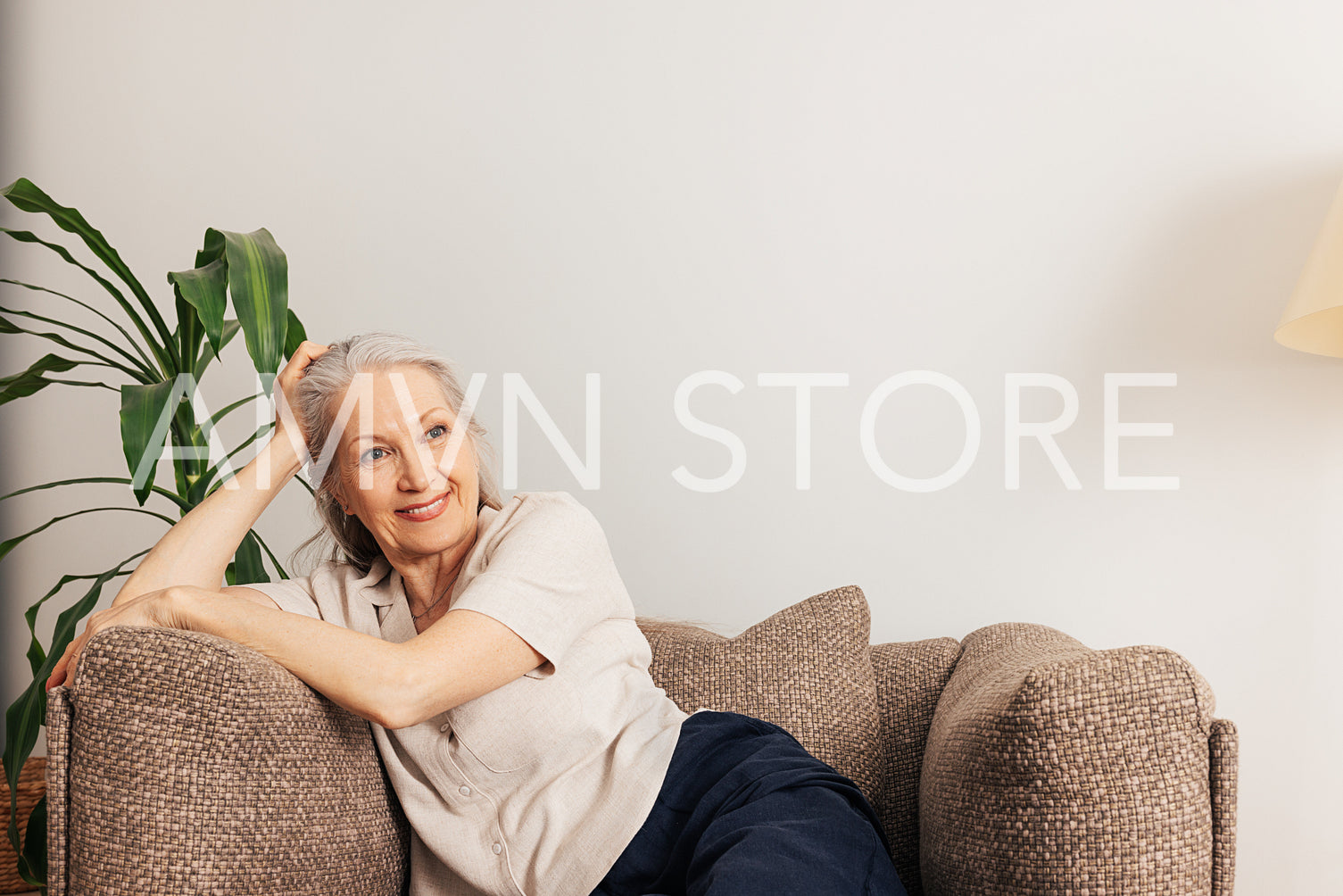 Pensive senior woman relaxing at home sitting in an armchair