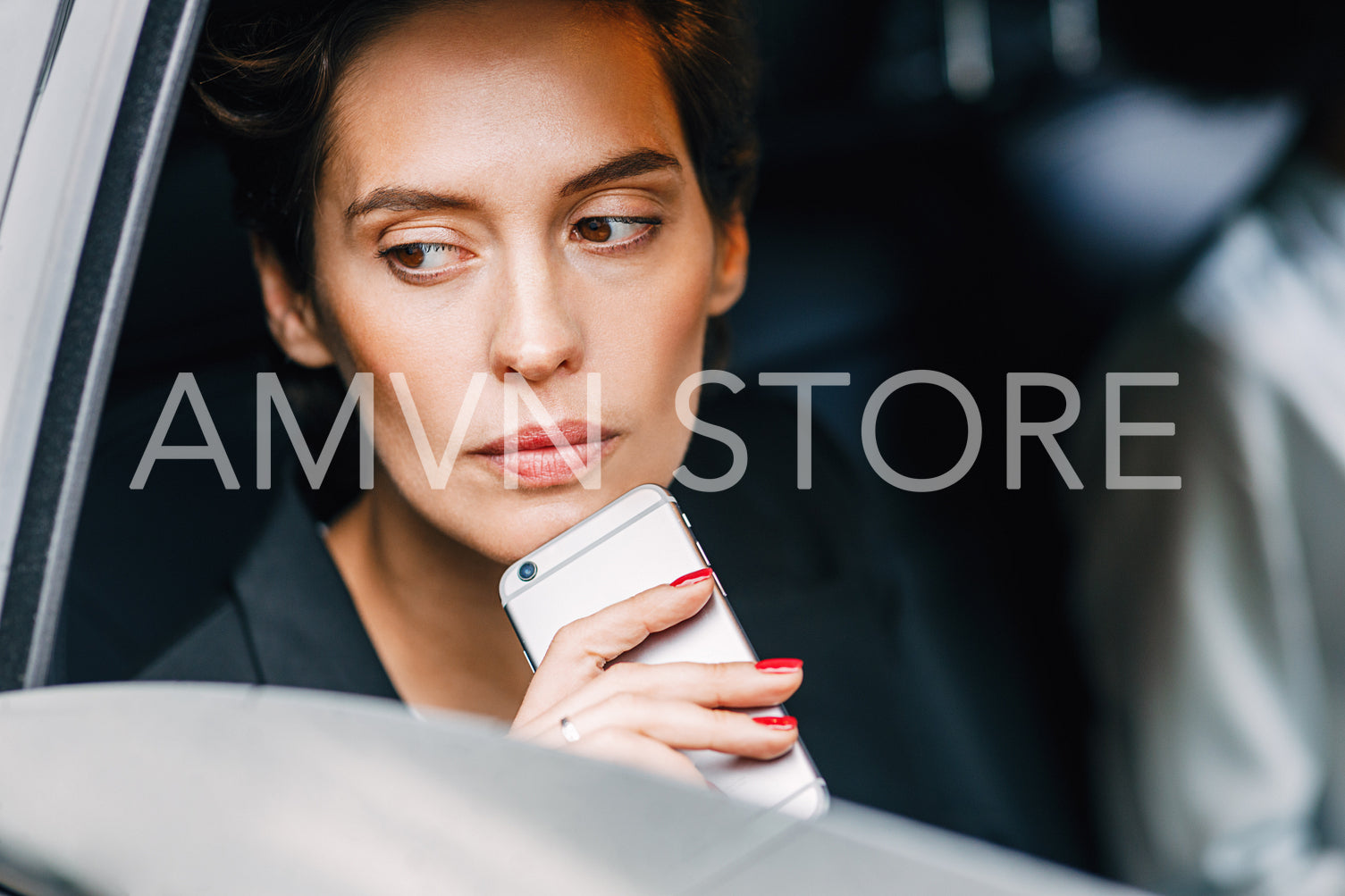 Thoughtful woman holding a cell phone while sitting on a backseat of a taxi