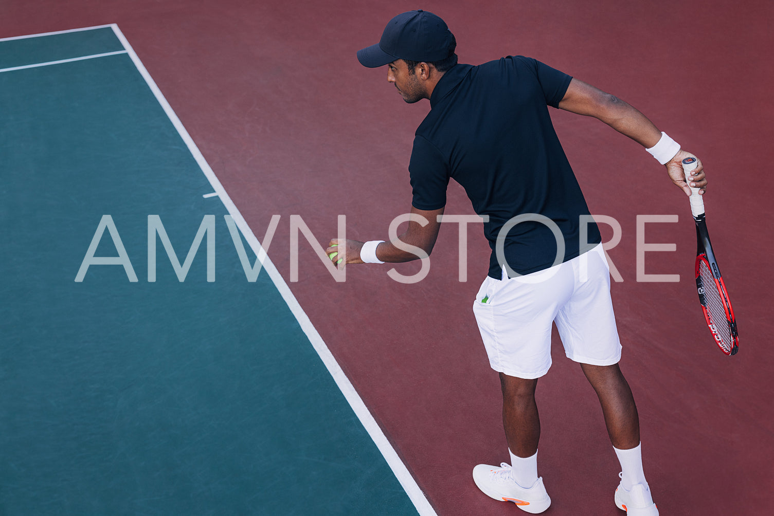 Young professional tennis player preparing to serve ball in a game, standing at baseline