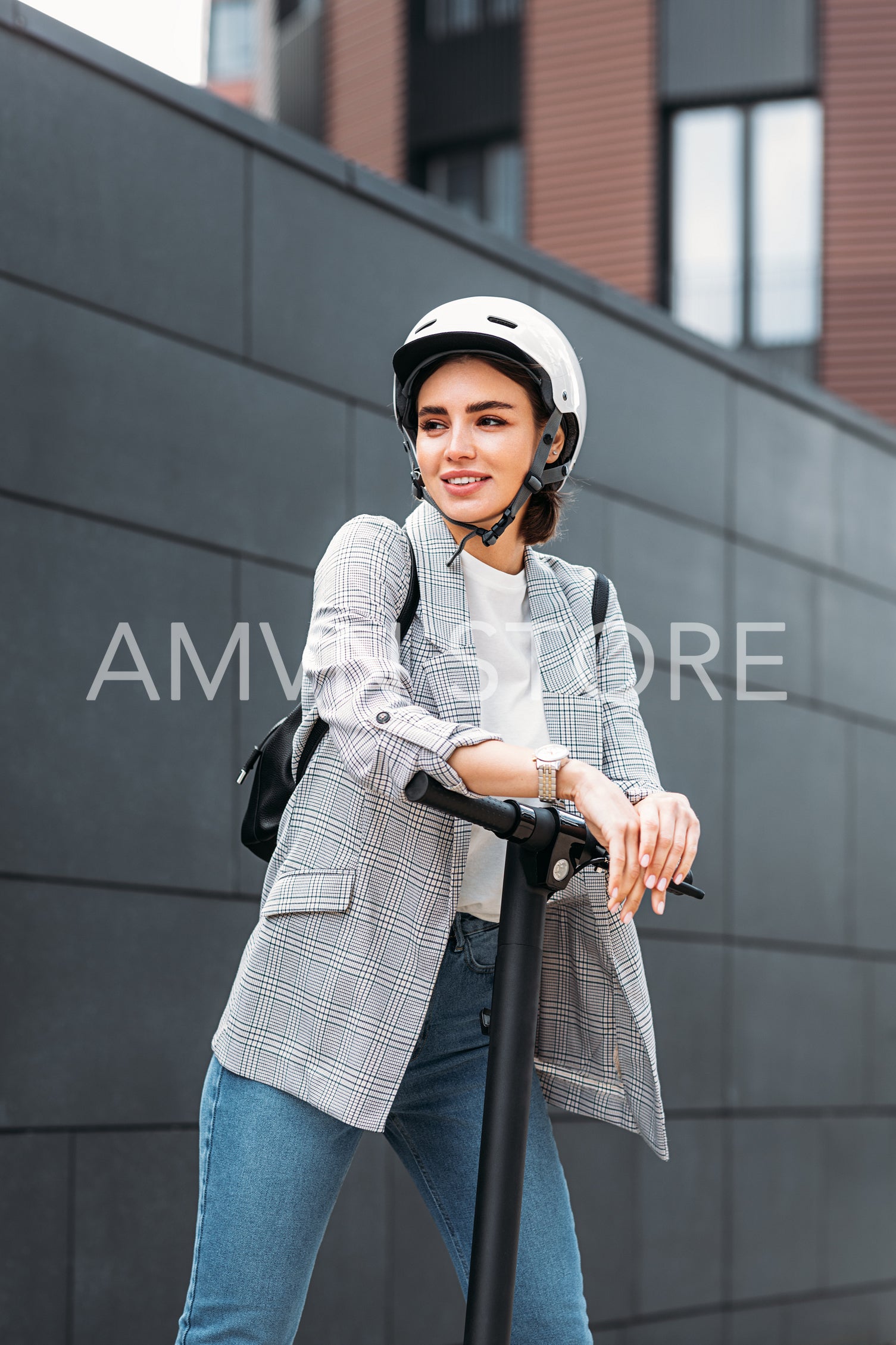 Businesswoman leaning on electric scooter and looking away. Portrait of young female holding scooter outdoors.