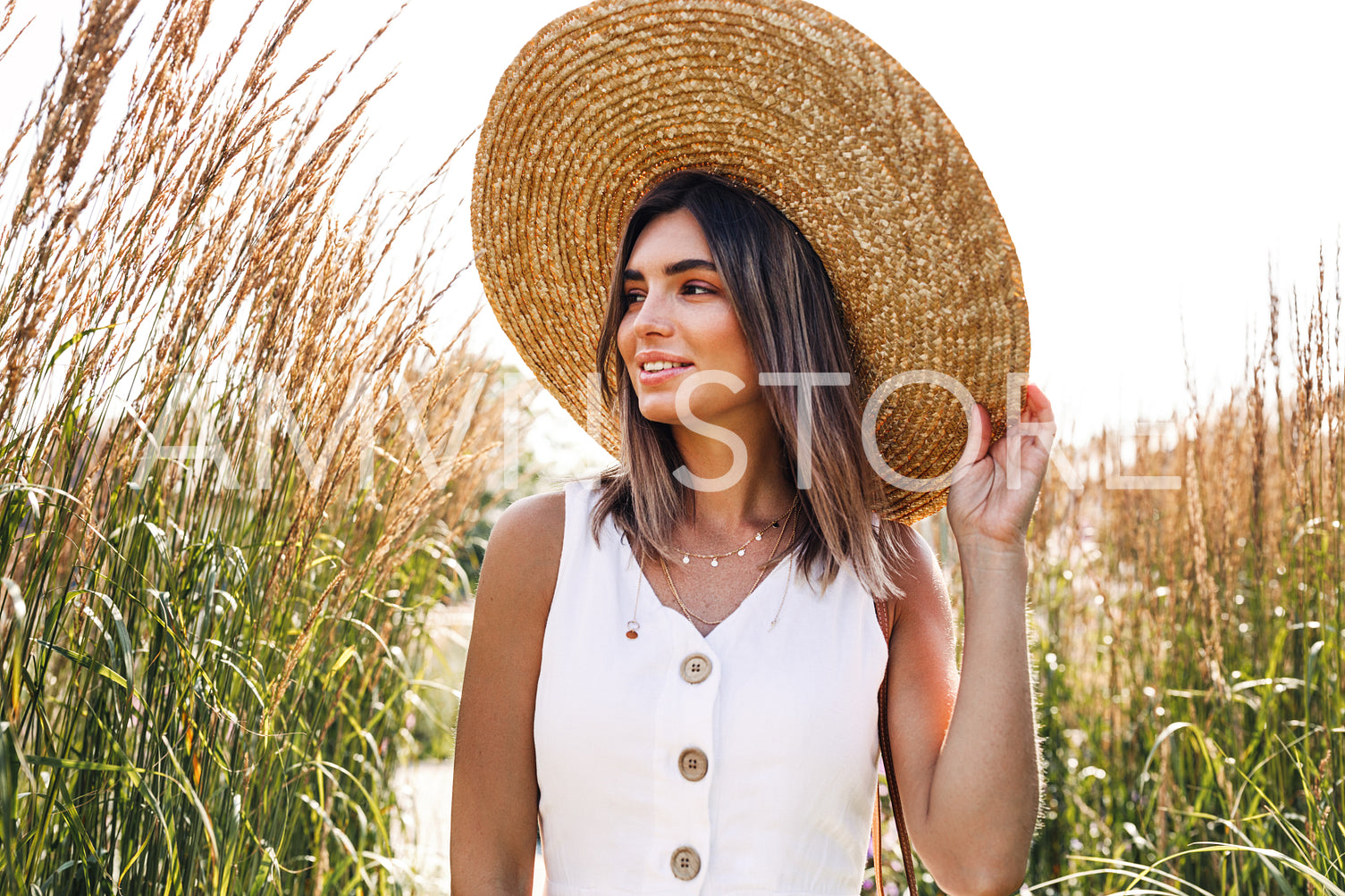 Young smiling woman wearing straw hat and walking in the park	