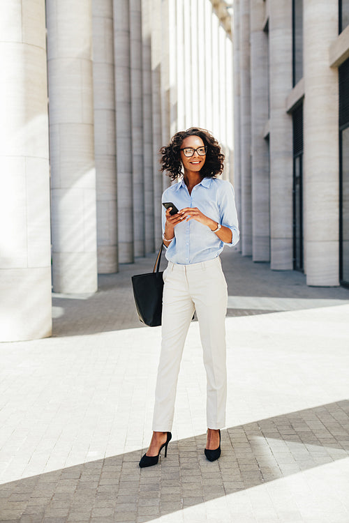 Businesswoman wearing formal clothes standing in front of a modern office building