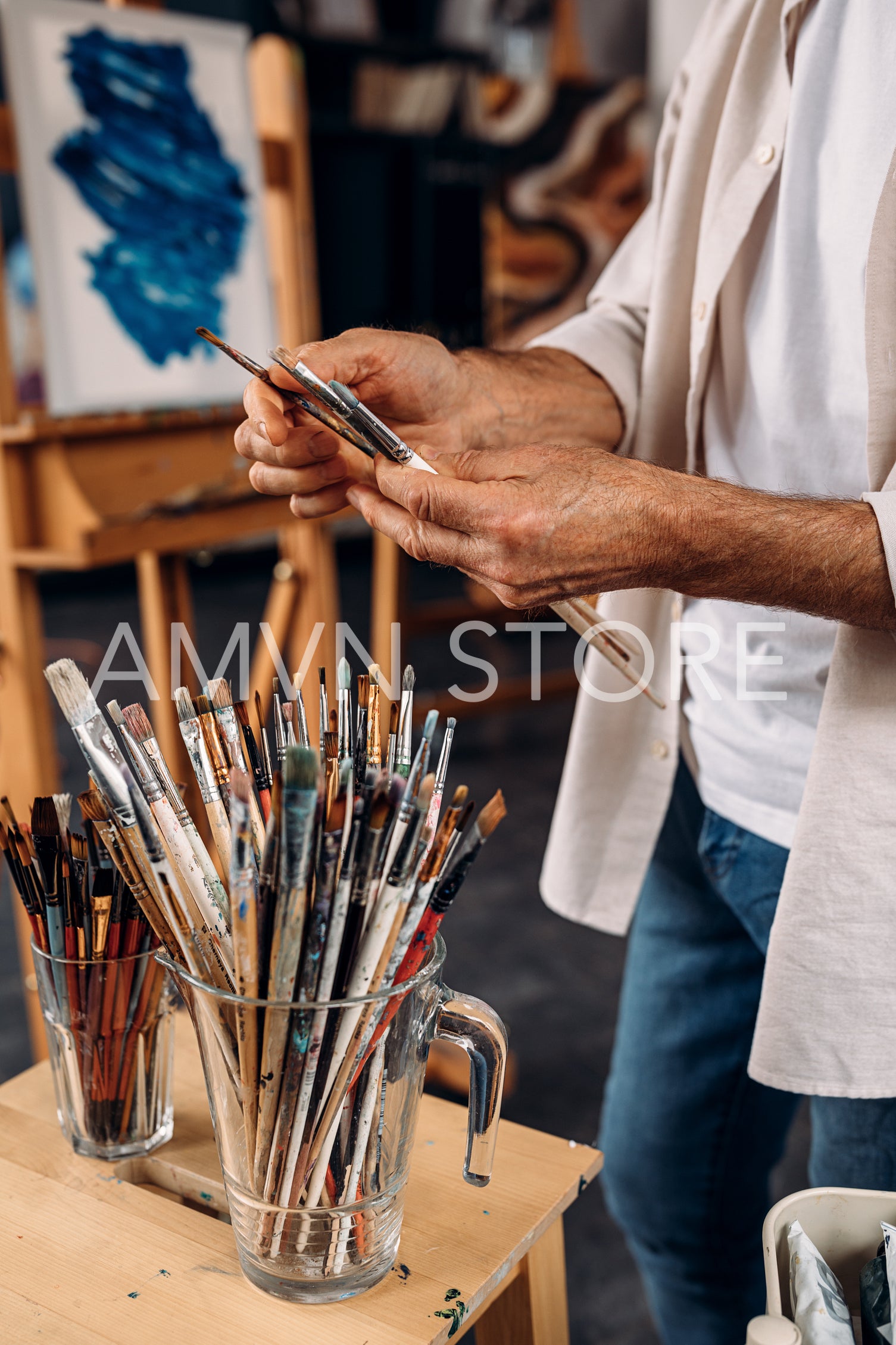 Cropped shot of artist choosing brushes in workshop	