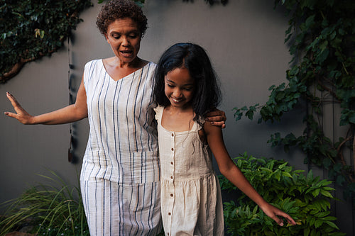 Happy grandma and granddaughter dancing together in backyard