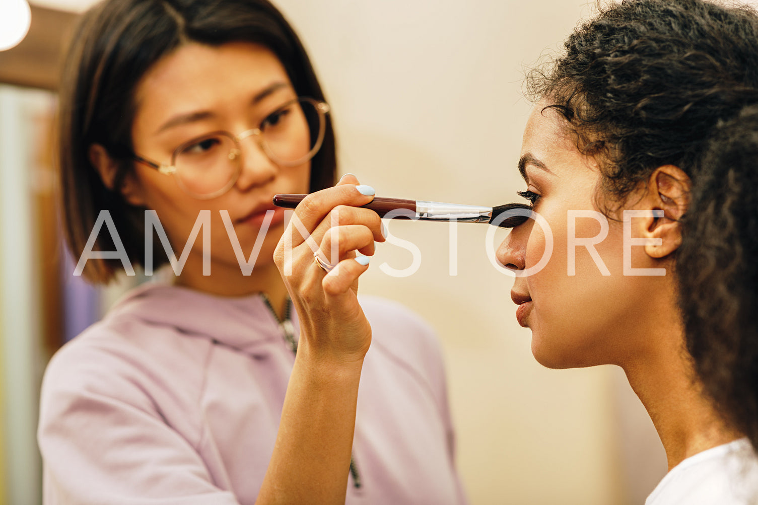 Close up of make up artist hand shading under the eyes of a model	
