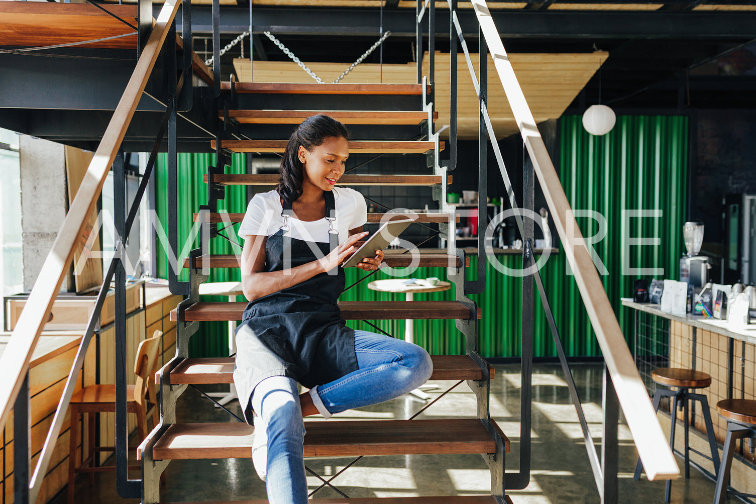 Coffee shop owner sitting on staircase and reviewing business files on digital tablet	