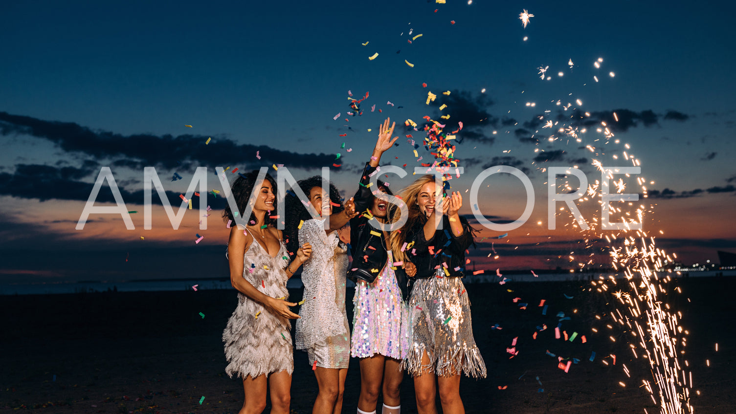 Four happy young female friends throwing confetti at sunset	