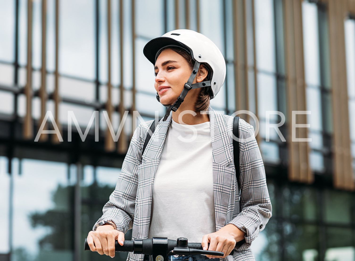 Beautiful woman in white cycling helmet holding a handlebar of electric scooter looking away