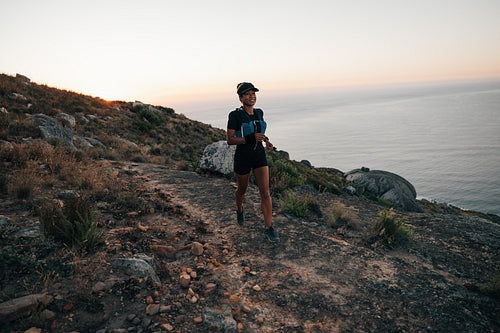 Trail runner exercising at sunset on mountain. Woman running on a hill.