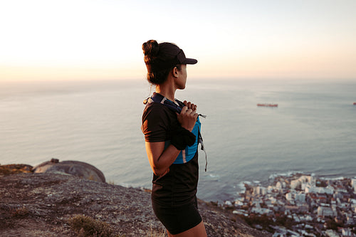 Side view of female hiker looking at the ocean at sunset from the top of the mountain