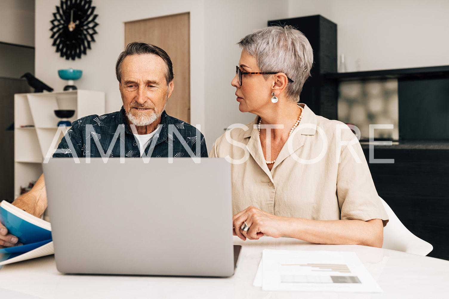 Senior people sitting at a table in a living room discussing bills