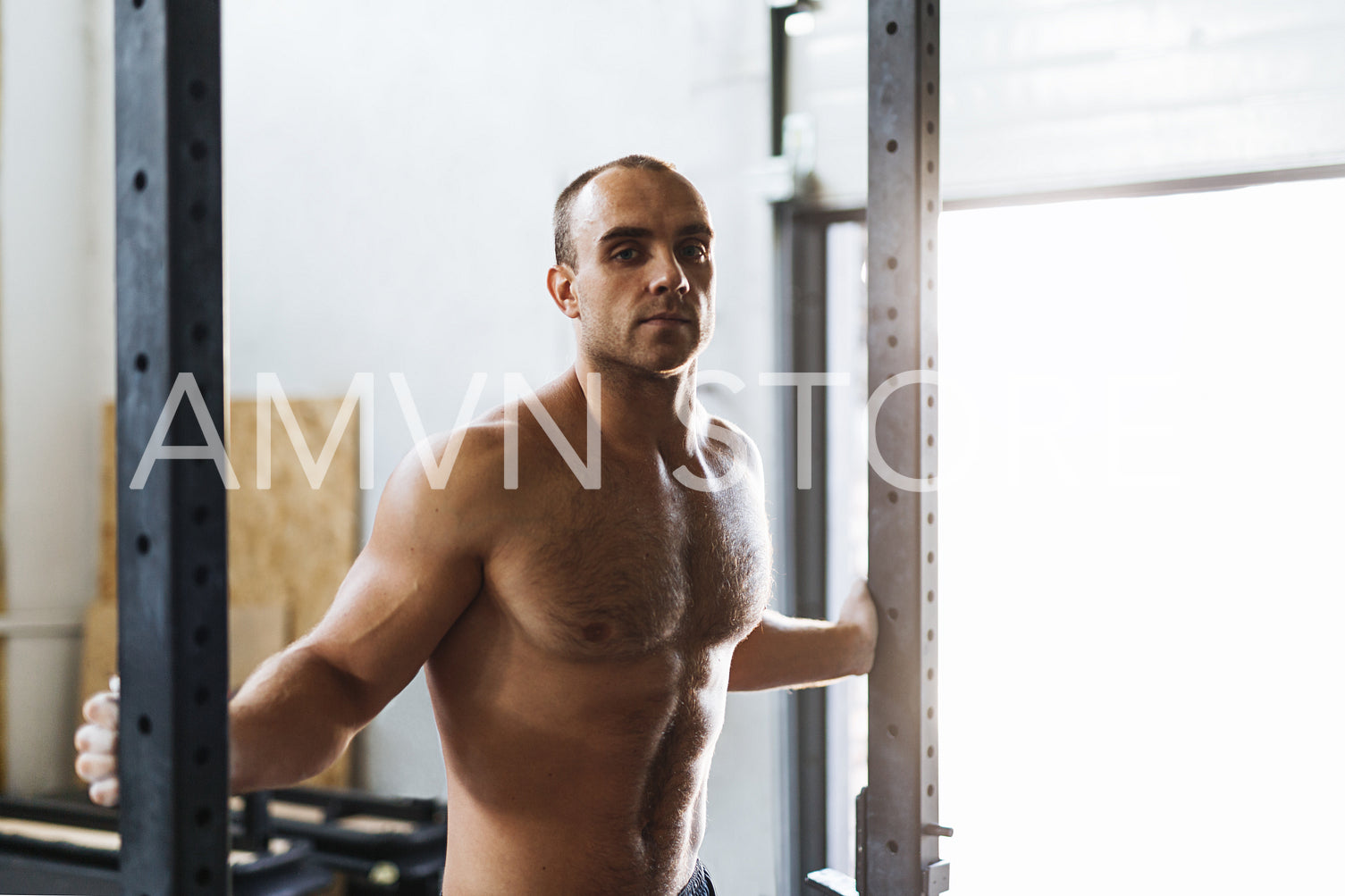 Young sportsman posing in gym, looking at camera	