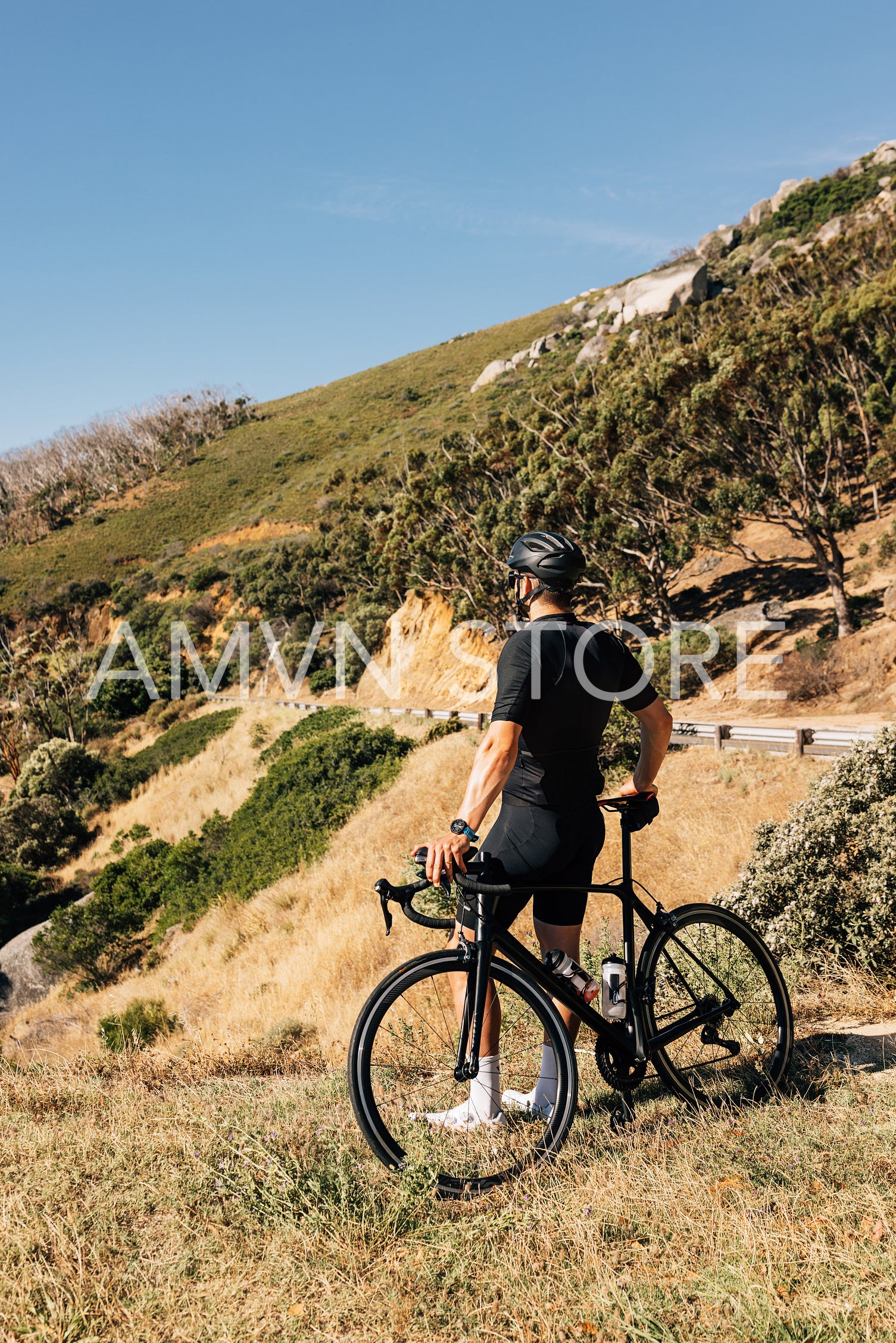 Rear view of a cyclist in black sportswear enjoying the view while relaxing during training