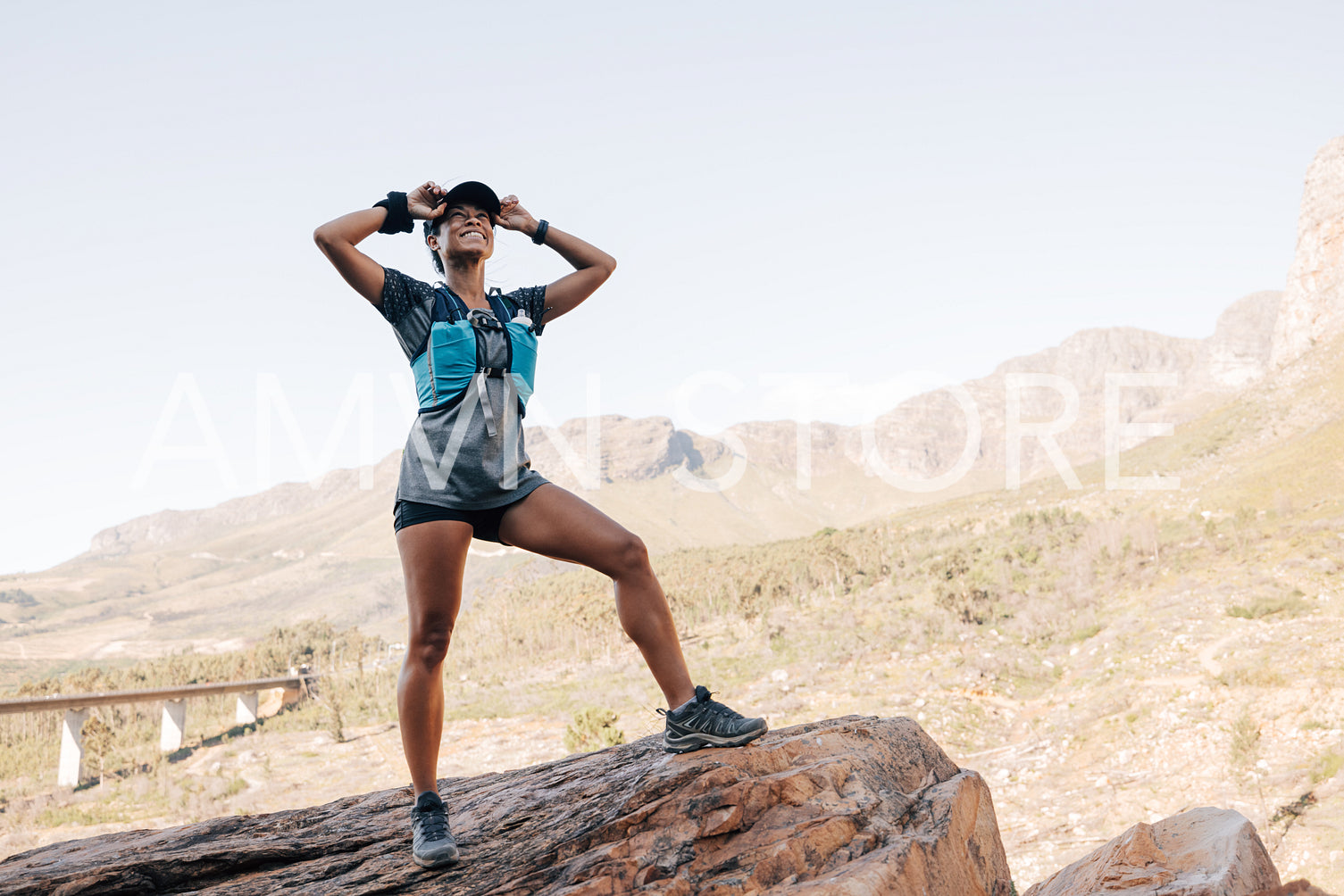 Happy female hiker in sportswear standing on a rock enjoying the view