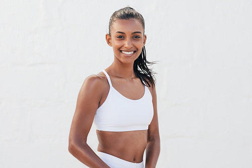 Portrait of a young slim female in fitness attire. Beautiful woman standing in an outdoor studio.