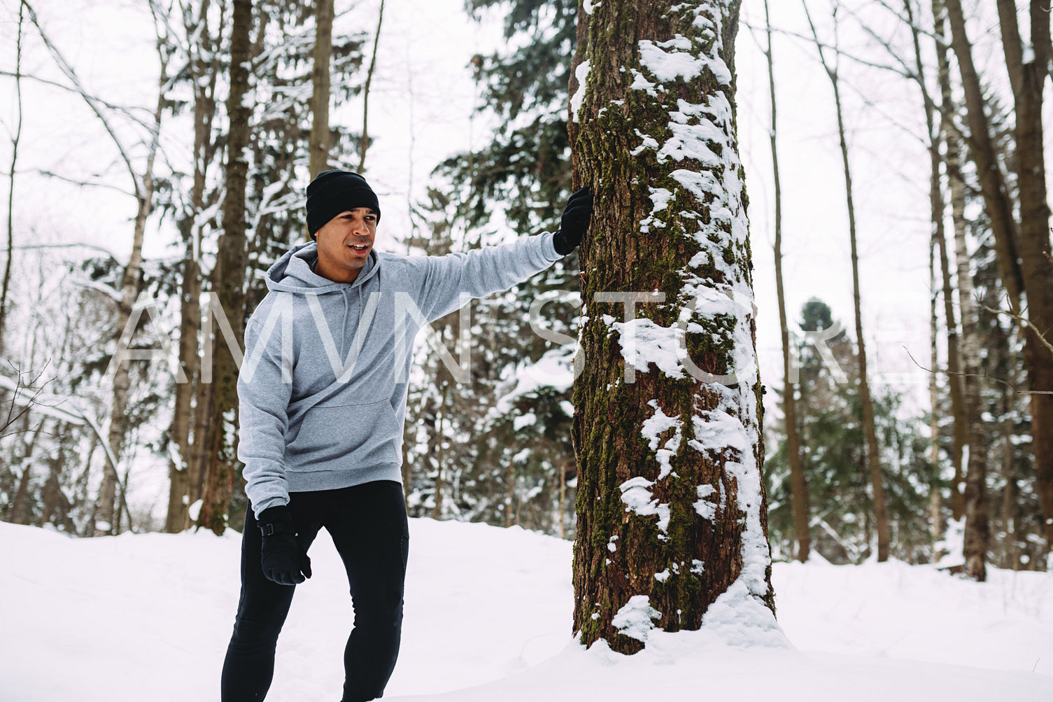 Young man resting after a workout at snowy forest	