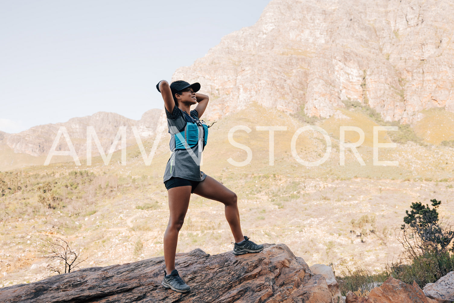 Side view of slim female standing with his hands behind head and taking a break after hiking