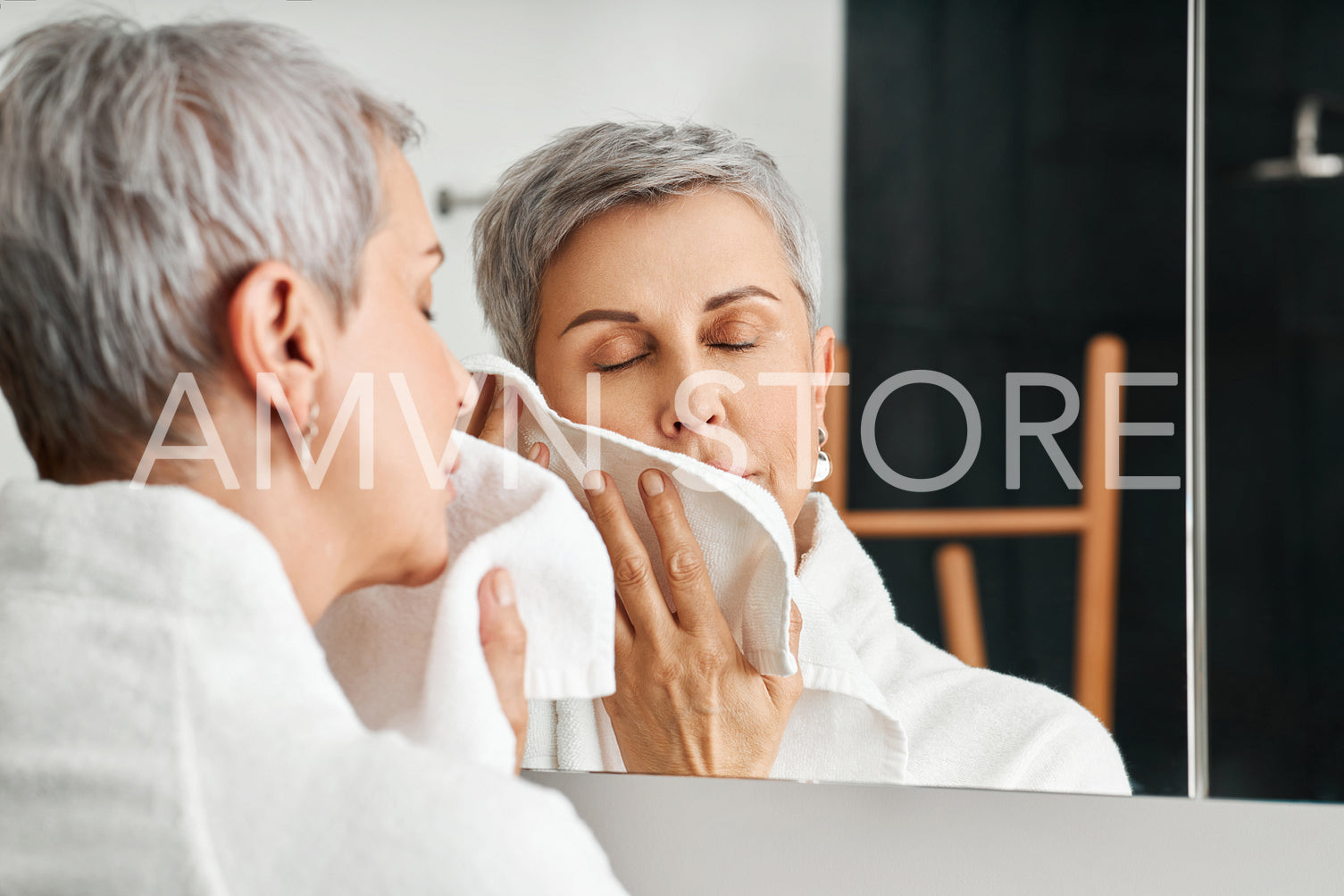 Mature woman with short grey hair using a towel after washing up face	