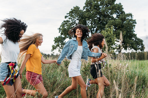 Group of a happy woman running and jumping outdoors. Female friends having fun on a field.