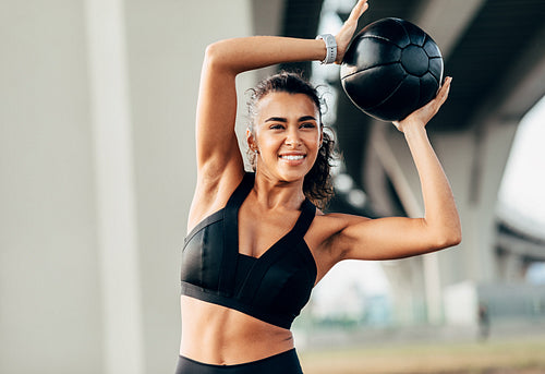 Young female doing warming up exercises with medicine ball