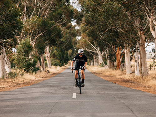 Professional female cyclist in sportswear riding bicycle on a centre of countryside road