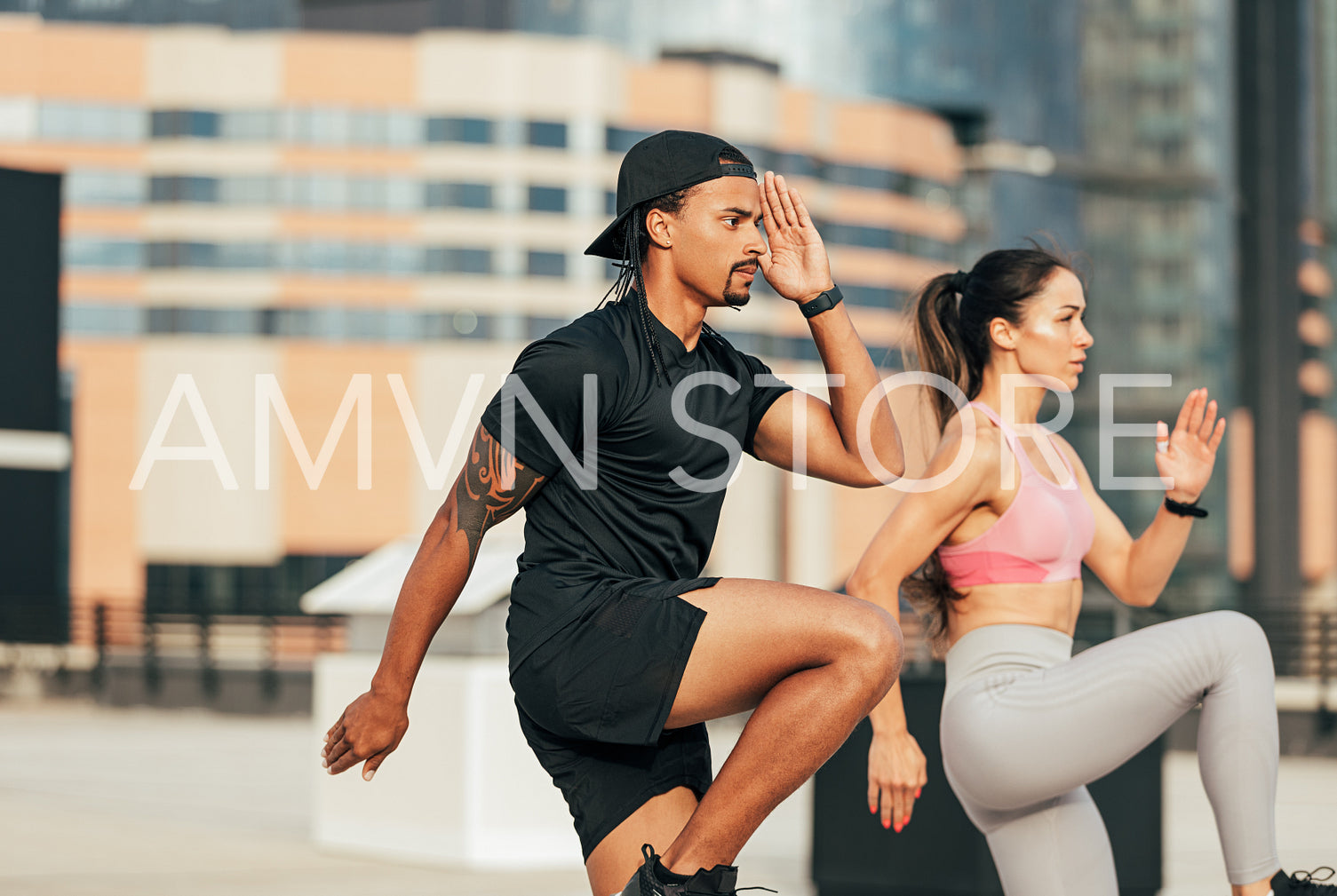 Fitness couple jumping together. Two athletes are warming up on a rooftop.