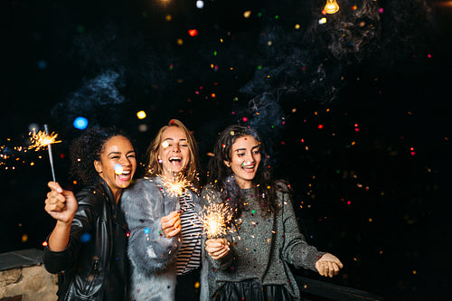 Three happy women having fun with sparklers. Outdoor party.