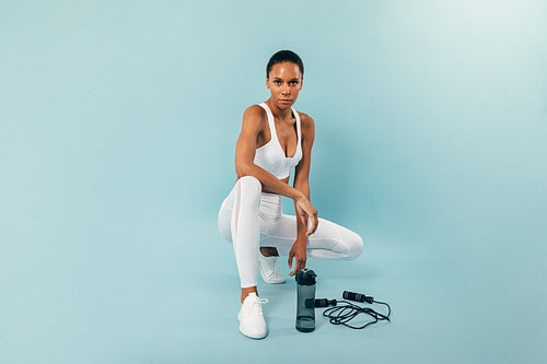 Young fit woman resting after training over a blue background in a studio looking at camera