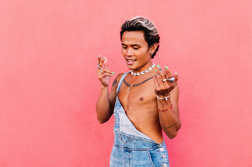 Stylish guy in denim dancing outdoors against pink wall