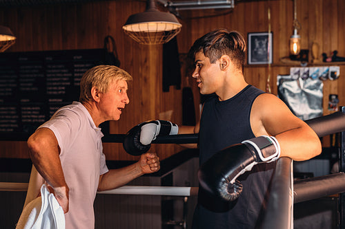 Male boxer listening to coach while standing in corner at ring