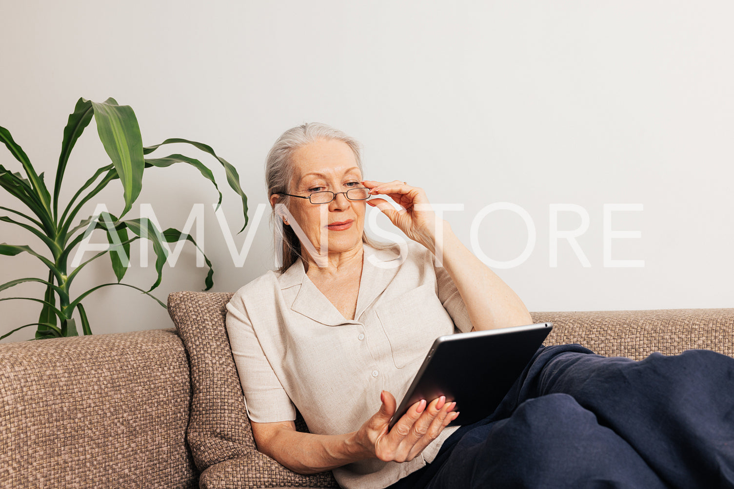 Aged woman in eyeglasses lying on sofa