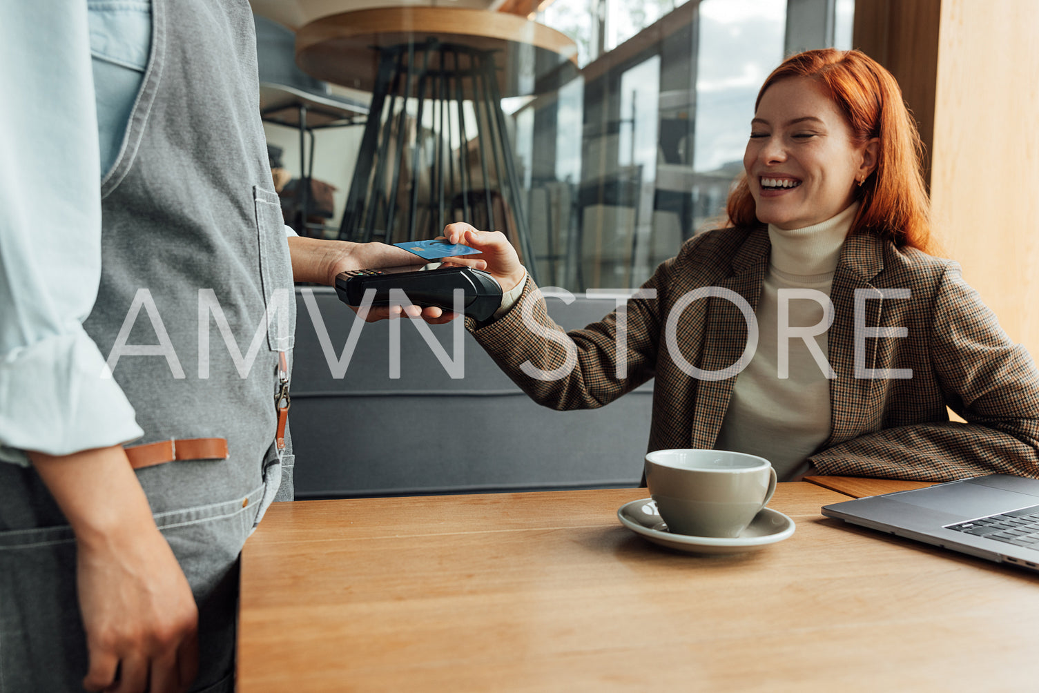 Happy woman paying for breakfast by card in coffee shop 