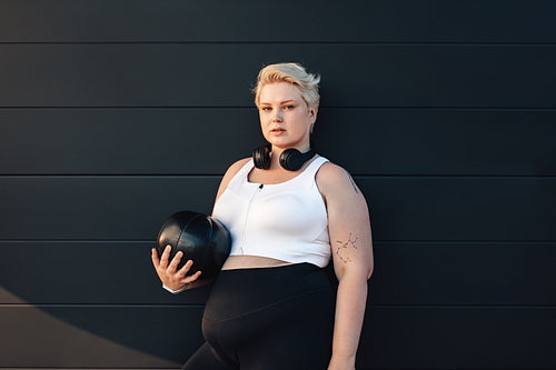 Young woman with a medicine ball at a black wall