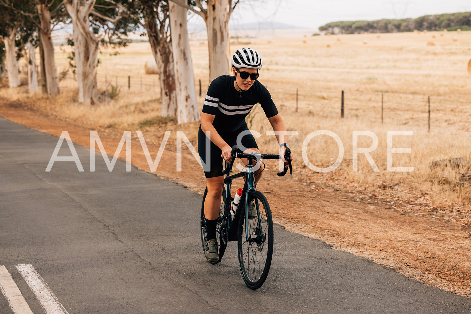 Young professional cyclist riding bicycle on countryside landscape. Fit sportswoman cycling outdoors.