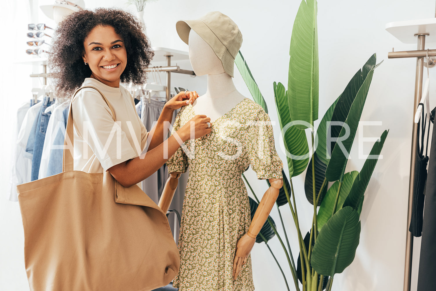 Young female with shopping bag looking at camera while standing at mannequin on boutique