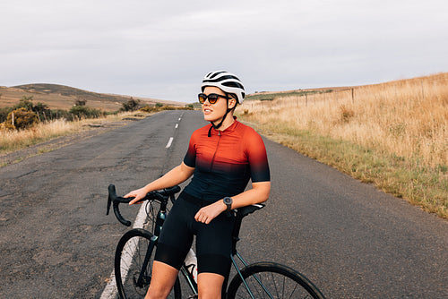 Portrait of female bicycle rider taking a break on country road sitting on bike