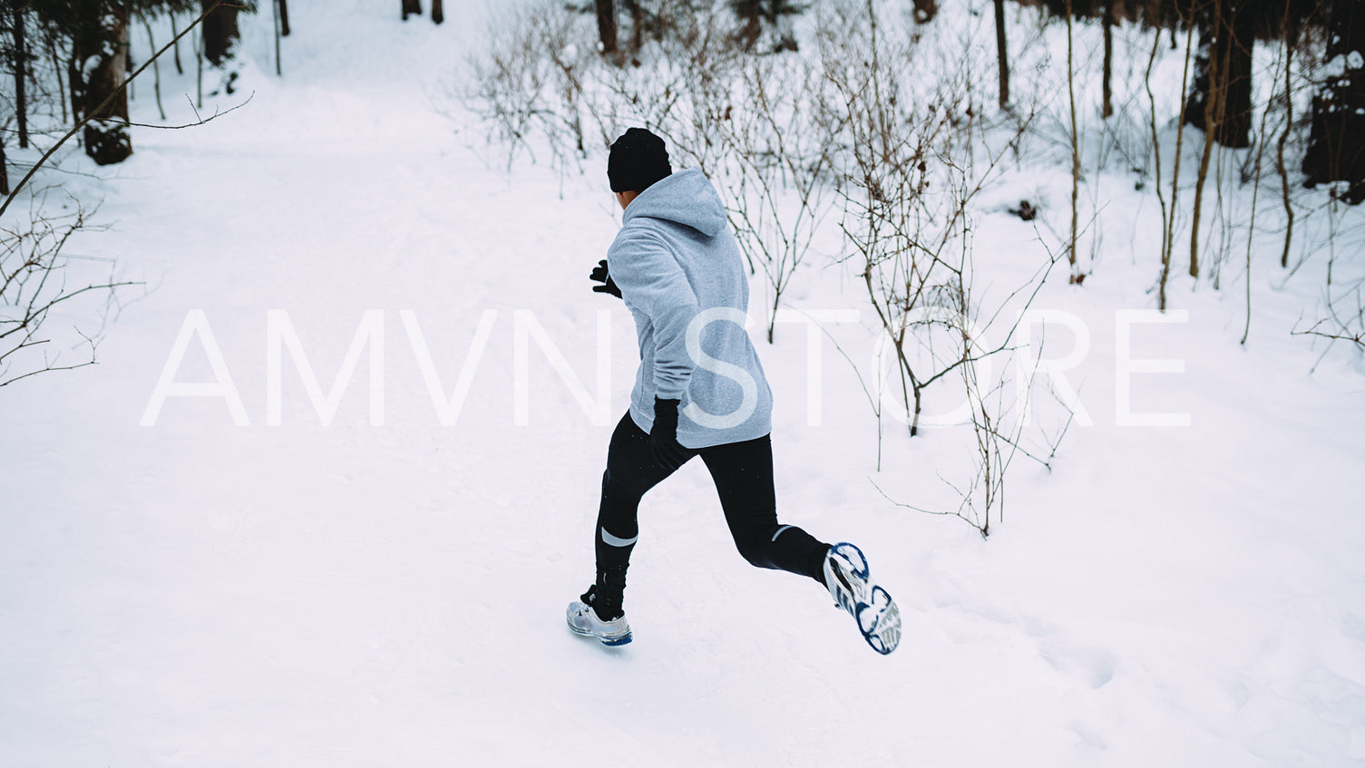 Rear view of young athlete running at path in forest	
