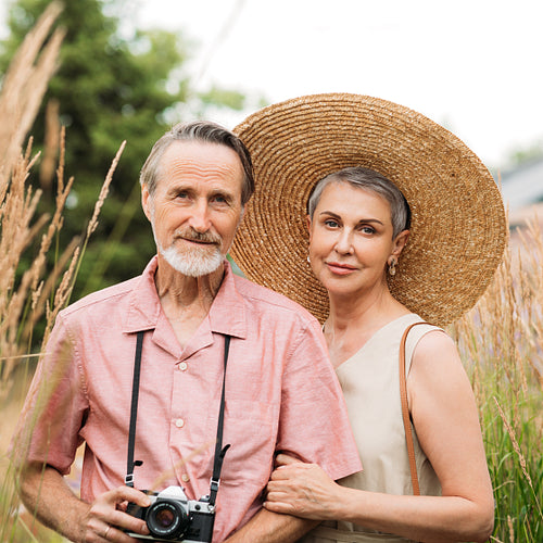 Portrait of two aged tourists standing on a wheat field