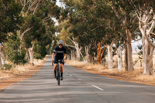 Woman riding bicycle on empty road. Cyclist rides her bike throu