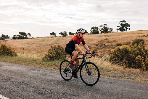 Young healthy cyclist riding a bike on countryside. Professional woman cyclist exercising.