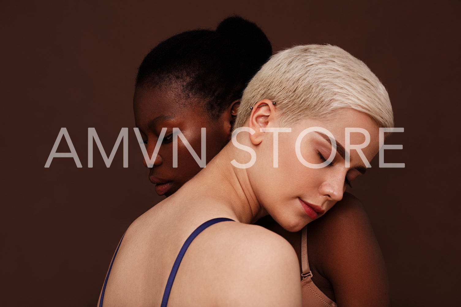 Two young women with different skin color standing together. Females put their heads on each other's shoulders with closed eyes.