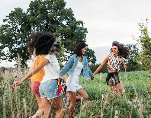 Happy females running on field enjoying summer journey