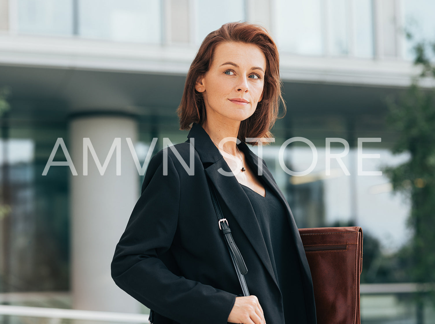 Portrait of a middle-aged businesswoman in formal clothes holding a leather folder and looking away while standing outdoors