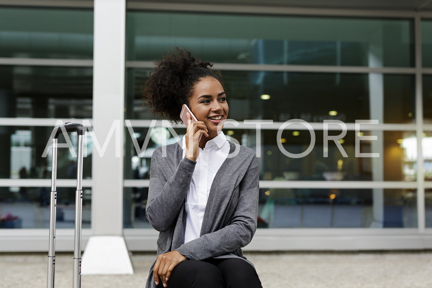 Happy businesswoman sitting at building, talking on mobile phone	