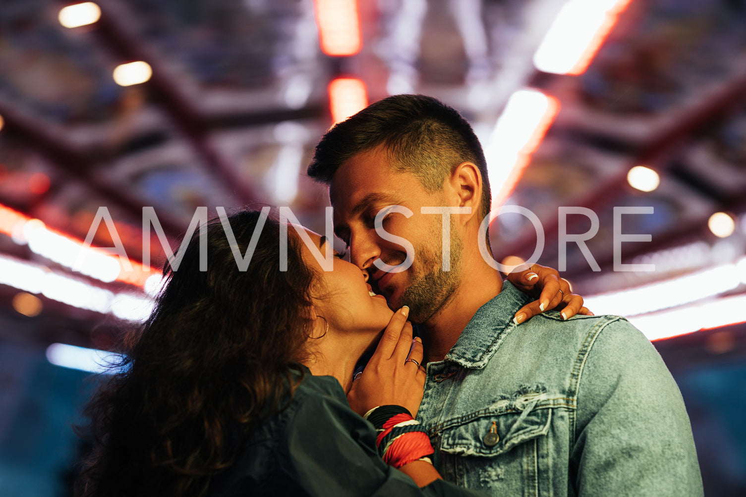 Young romantic couple against night lights in an amusement park